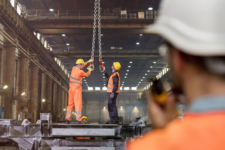 Robotnicy na platformie w hali produkcyjno-montażowej